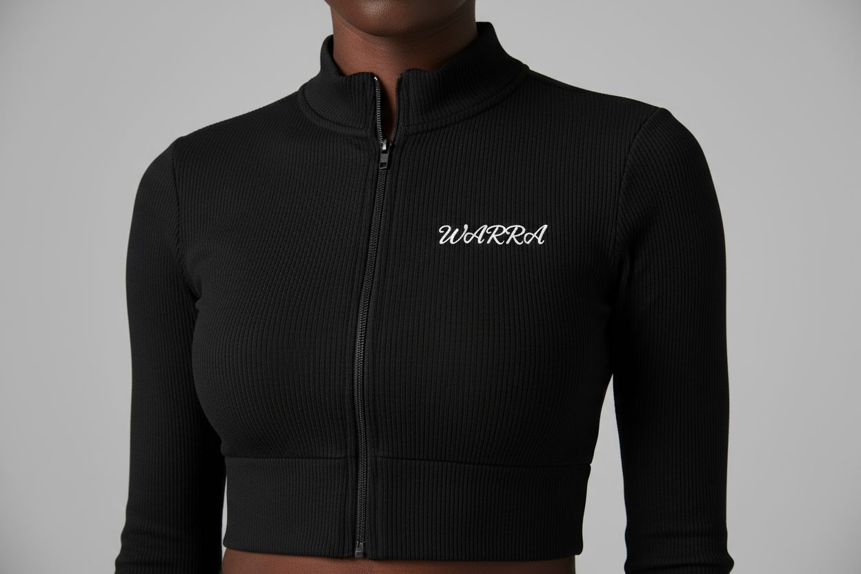 CLOSE-UP STUDIO PHOTO OF A BLACK FEMALE MODEL WEARING A BLACK RIBBED LONG-SLEEVE CROPPED ZIP TOP LIKE THE REFERENCE IMAGE.
FABRIC TEXTURE MUST BE CLEAR — TIGHT RIBBED KNIT, SMOOTH AND STRETCHY.
“WARRA” WRITTEN IN SMALL WHITE CURSIVE ACROSS THE UPPER CHEST, CENTERED LIKE A NIKE LOGO.
THE CURSIVE FONT MUST BE REALISTIC, FLOWING, AND ELEGANT WITH A DISTINCT “W”.
SOFT STUDIO LIGHTING, NEUTRAL BACKGROUND, FOCUS ON FABRIC AND LOGO DETAIL.
NO TEXT, NO DISTRACTIONS, JUST MODEL AND TOP.